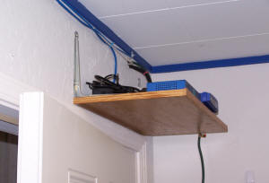 Router and PoE switch mounted on shelf above door.